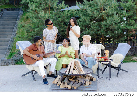 Friends celebrating together in summer at a picnic with wine and guitar 137337589