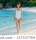 身穿白色泳衣的可愛女子在海灘上散步 137337769