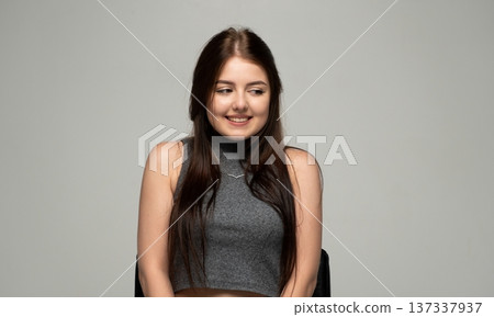 Young smiling brunette woman looking away, expressing shyness or thoughtful happiness in a studio portrait 137337937