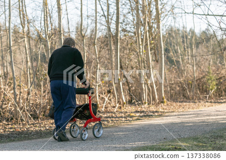 Senior man taking a walk with walker in the park. Senior man taking a walk with walker in the park. 137338086