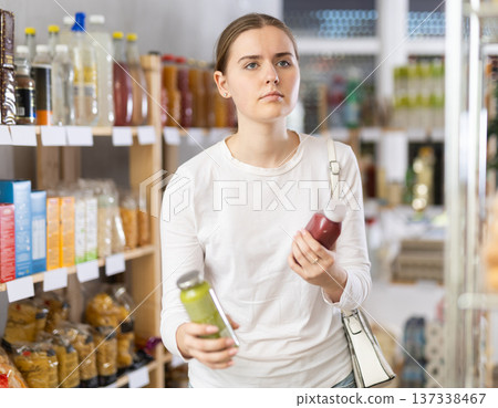 Girl customer in supermarket examines smoothie, chooses food-stuff in health lifestyle store 137338467