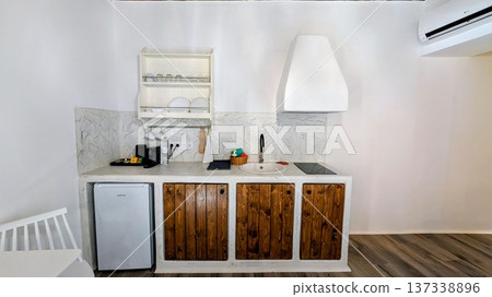 Compact kitchen with mini-fridge, coffee maker, and dishes and cups on wall rack Compact kitchen with mini-fridge, coffee maker, and dishes and cups on wall rack 137338896