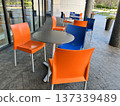 Orange and Blue Chairs and Round Tables in Street Cafe. 137339489