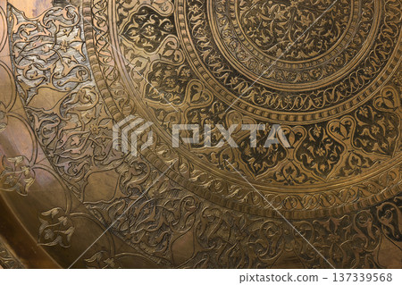 Ornate brass plate featuring detailed engraved patterns Ornate brass plate featuring detailed engraved patterns 137339568