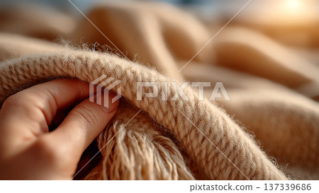 一隻手輕輕撫摸著柔軟的米色針織面料的特寫鏡頭 137339686