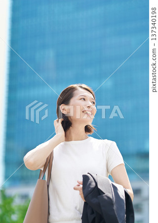 Businesswoman taking off her jacket outdoors Businesswoman taking off her jacket outdoors 137340198