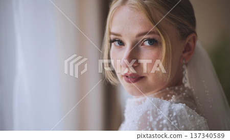 Beautiful blonde bride looking over her shoulder while wearing her white wedding dress on her wedding day Beautiful blonde bride looking over her shoulder while wearing her white wedding dress on her wedding day 137340589
