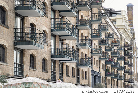 a multi-story building characterized by its brick facade, arched windows and numerous balconies with dark-colored railings. a multi-story building characterized by its brick facade, arched windows and numerous balconies with dark-colored railings. 137342155