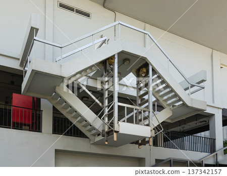 A sculptural focal point is created by this industrial staircase, which is integrated into the Bank of Thailand Learning Center's modern white facade. Because of a daring asymmetrical cantilever. 137342157