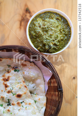 Delicious Indian Palak Paneer Curry with Garlic Naan Bread on Wooden Table Delicious Indian Palak Paneer Curry with Garlic Naan Bread on Wooden Table 137342518
