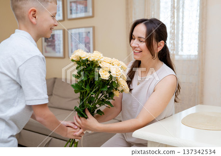 Teenage boy giving mother a bouquet of yellow roses for Mother's Day or International Women's Day 137342534