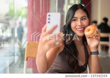 Young Woman Taking Selfie with Donut in Cafe Young Woman Taking Selfie with Donut in Cafe 137342554