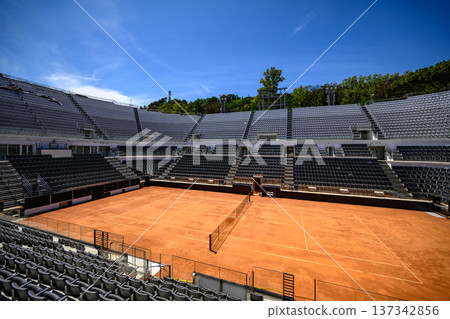 Large outdoor tennis stadium with clay court and blue sky Large outdoor tennis stadium with clay court and blue sky 137342856