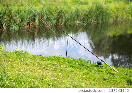 Fishing rod on holder by the lake, ready for catch Fishing rod on holder by the lake, ready for catch 137343343