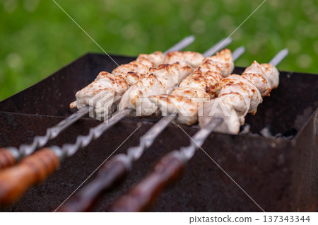 Shashlik on skewers grilling over charcoal in summer day Shashlik on skewers grilling over charcoal in summer day 137343344