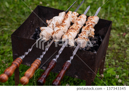 Shashlik on skewers grilling over charcoal in summer day 137343345