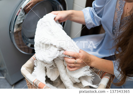 Woman taking dirty laundry from basket to washing machine in bathroom Woman taking dirty laundry from basket to washing machine in bathroom 137343365