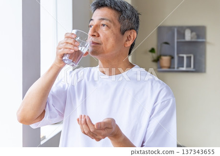 Senior man taking medicine by the window 137343655