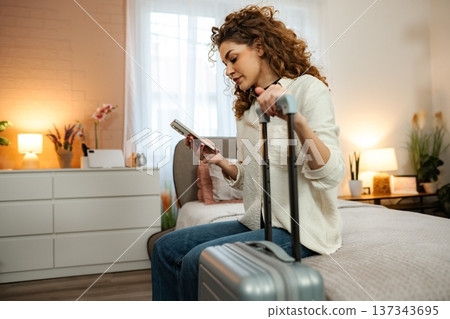 Woman planning travel trip with mobile phone in bedroom Woman planning travel trip with mobile phone in bedroom 137343695