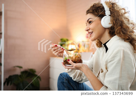 Young woman eating healthy breakfast while listening to music Young woman eating healthy breakfast while listening to music 137343699