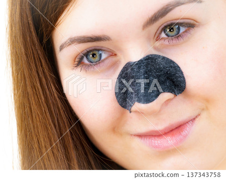 Woman applying pore strips on nose Woman applying pore strips on nose 137343758