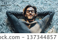 Man lying on a large amount of cash while relaxing indoors at a private space during daytime 137344857