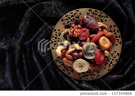 Dried tropical fruits and nuts in a golden bowl. Dried tropical fruits and nuts in a golden bowl. 137344868