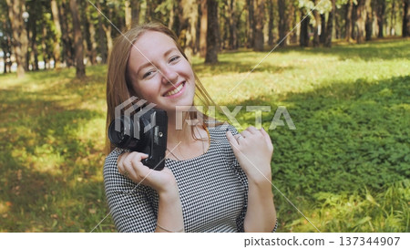 Professional photographer grinning, gripping camera amid lush greenery under bright sunlight Professional photographer grinning, gripping camera amid lush greenery under bright sunlight 137344907