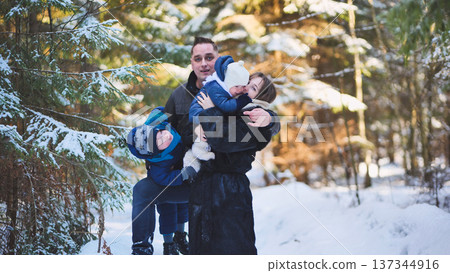 Family having fun together during a winter day in a snowy forest, enjoying the crisp air and beautiful scenery 137344916