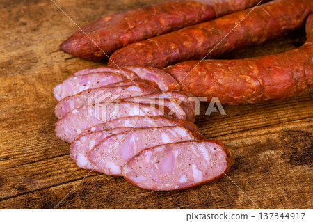 Sausage links are placed on wood with few slices showing inner texture highlighting preparation for meal. Sausage links are placed on wood with few slices showing inner texture highlighting preparation for meal. 137344917