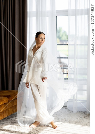 Bride wearing white pajamas and veil getting ready for wedding ceremony Bride wearing white pajamas and veil getting ready for wedding ceremony 137344927