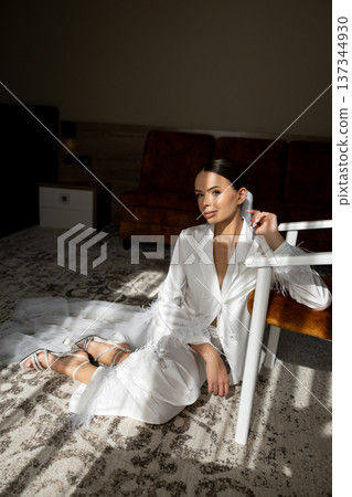 Bride wearing white suit sitting on carpet in hotel room Bride wearing white suit sitting on carpet in hotel room 137344930