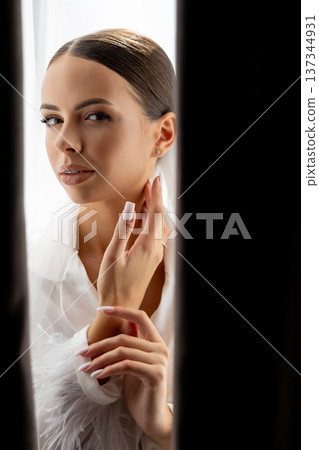 Bride hiding behind curtains looking down with closed eyes and hands near her face Bride hiding behind curtains looking down with closed eyes and hands near her face 137344931