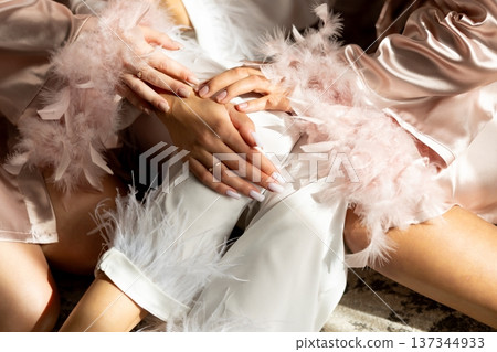 Bridesmaids wearing elegant pajamas with feathers are relaxing before wedding ceremony Bridesmaids wearing elegant pajamas with feathers are relaxing before wedding ceremony 137344933