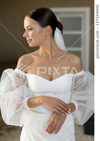 Bride wearing white wedding dress with puffy sleeves posing indoors Bride wearing white wedding dress with puffy sleeves posing indoors 137344940