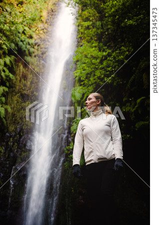 Solo trekker stands quietly beneath lush green canopy while contemplating 137345473