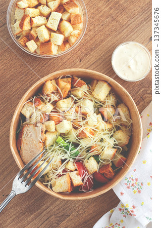 Caesar salad in a paper container, take it on the way, with sauce and croutons, on the table, snack, no people, 137345676