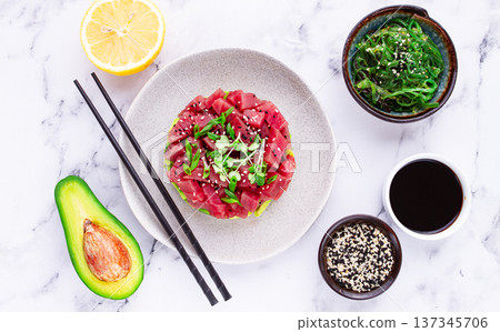 Fresh tuna tartare with avocado served on a marble table with soy sauce and seaweed salad 137345706