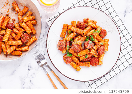 rigatoni pasta with spicy sausage, and rich tomato sauce served, on a white plate, homemade, 137345709