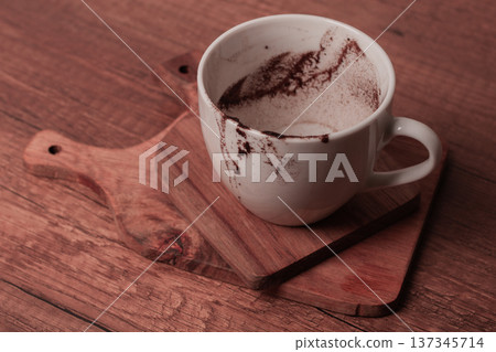 Cup sitting on a wooden surface with traces of coffee remains after a warm drink enjoyed at home 137345714