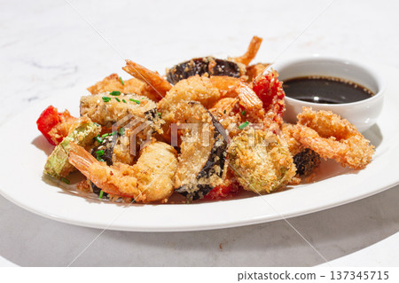 Shrimp and vegetable tempura, served with dipping sauce, on a white plate 137345715