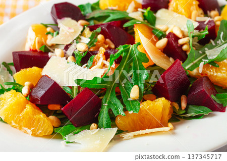 Fresh salad with beets, oranges, and arugula topped with cheese and nuts served on a white plate Fresh salad with beets, oranges, and arugula topped with cheese and nuts served on a white plate 137345717