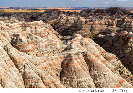 Scenic sunny view of the deeply eroded and colorful layered rock formations from White River Valley Overlook in Badlands National Park, South Dakota, United States. Scenic sunny view of the deeply eroded and colorful layered rock formations from White River Valley Overlook in Badlands National Park, South Dakota, United States. 137345854