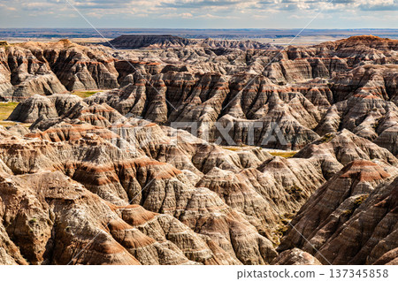 Scenic sunny view of the rugged and colorful eroded rock formations from Burns Basin Overlook in Badlands National Park, South Dakota, United States. Scenic sunny view of the rugged and colorful eroded rock formations from Burns Basin Overlook in Badlands National Park, South Dakota, United States. 137345858