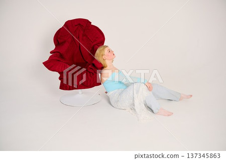 Relaxed woman barefoot on studio floor dressed in blue and denim jeans 137345863