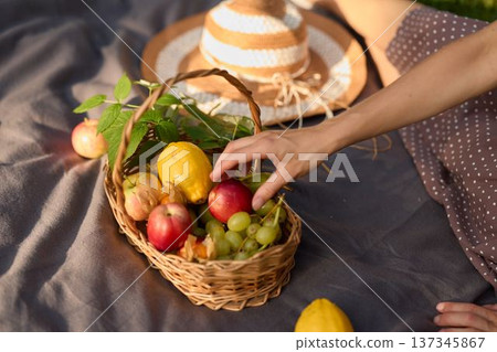 Hand reaching for apple in basket during golden hour Hand reaching for apple in basket during golden hour 137345867