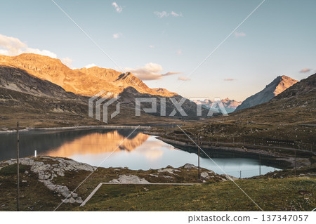 Lago Bianco glistens in the late afternoon sun, surrounded by majestic Alpine mountains in the Bernina Pass of Graubunden, Switzerland, showcasing nature's beauty and tranquility. Lago Bianco glistens in the late afternoon sun, surrounded by majestic Alpine mountains in the Bernina Pass of Graubunden, Switzerland, showcasing nature's beauty and tranquility. 137347057