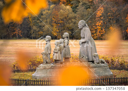 In Granny Valley, Ratiborice, Czechia, a statue depicts a loving grandmother and her grandchildren amidst vibrant autumn leaves. This memorial honors the writer Bozena Nemcova. 137347058