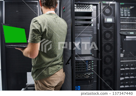 Data center technician troubleshooting servers with laptop in modern server room environment 137347440