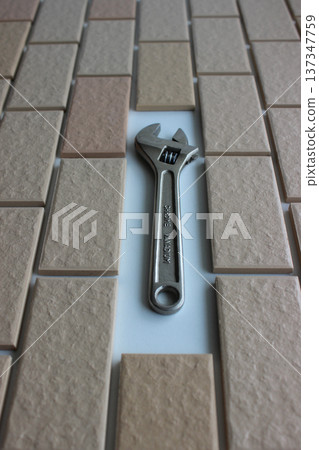Opened Jaws Of Chrome Adjustable Wrench On Free Space In Surface Covered Brick Tiles. Home Renovation Stock Photo For Vertical Story Opened Jaws Of Chrome Adjustable Wrench On Free Space In Surface Covered Brick Tiles. Home Renovation Stock Photo For Vertical Story 137347759